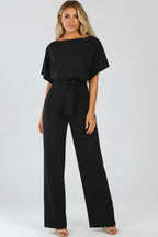 Front view of a black jumpsuit with loose kimono sleeves, tie belt and wide flowing trouser legs