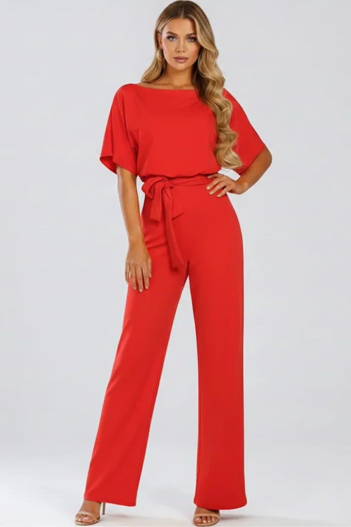 Model wearing a red jumpsuit with tied waist belt, loose sleeves and wide straight-leg trousers