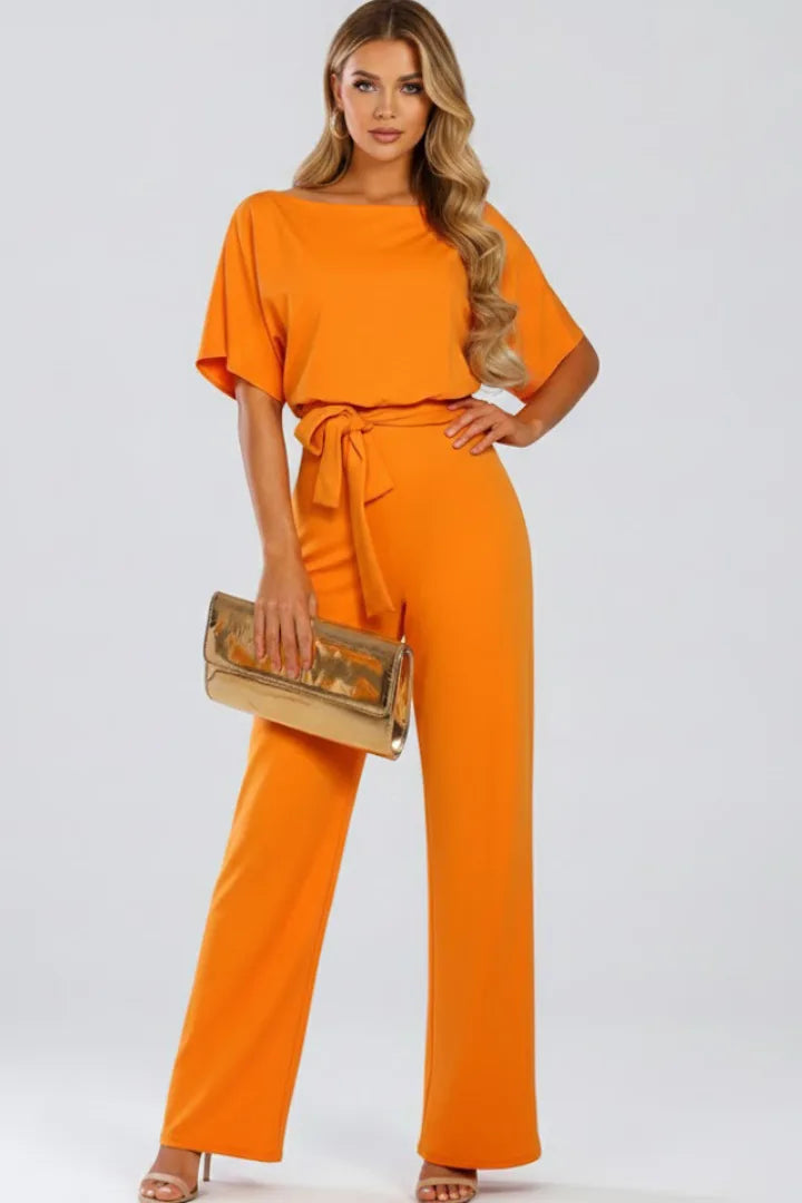 Orange jumpsuit with boat neck, relaxed short sleeves and a waist tie, styled with a metallic gold clutch