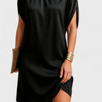 Side-angle crop of the black dress highlighting the curved hemline and smooth satin-like fabric texture