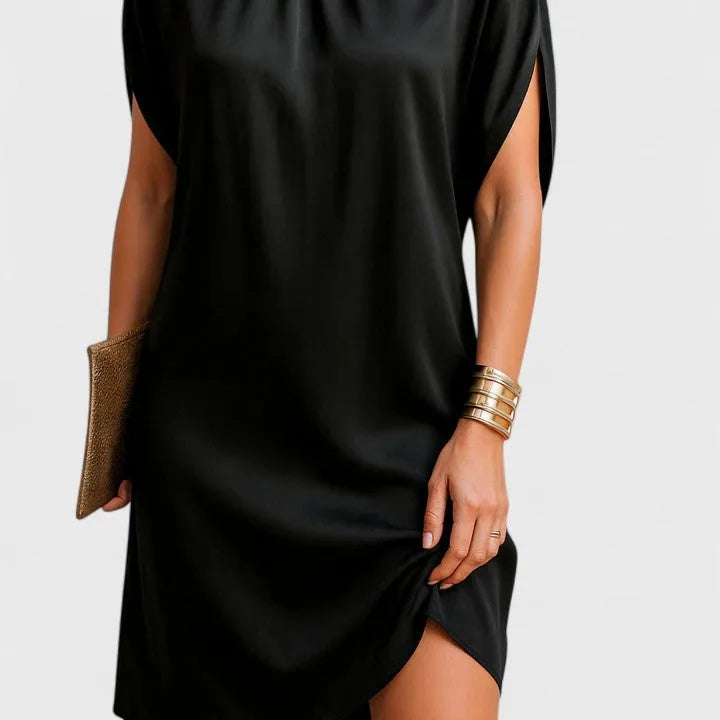 Side-angle crop of the black dress highlighting the curved hemline and smooth satin-like fabric texture
