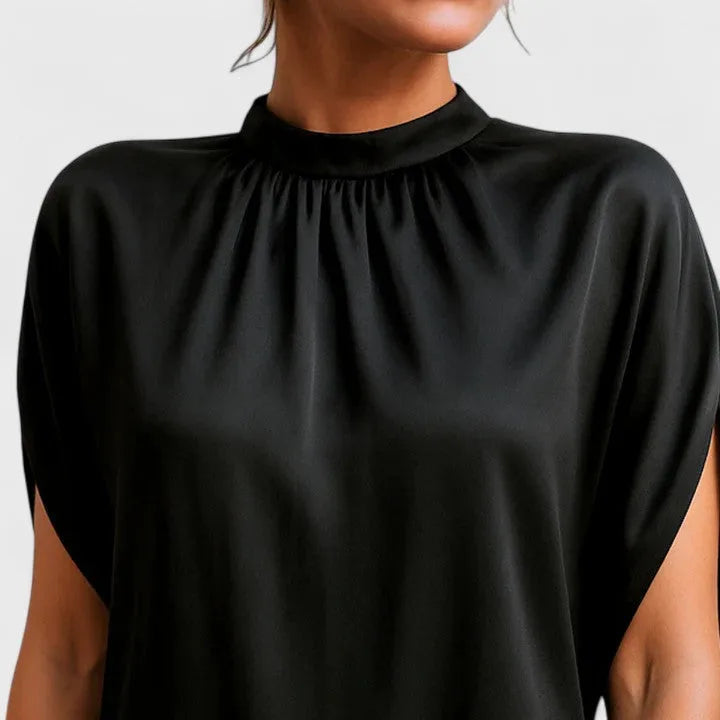 Detail shot of the gathered mock neckline and split short sleeve seam on the black satin-finish dress
