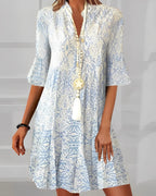 Indoor studio shot showing the tiered skirt and ruffled hem of the blue paisley three-quarter sleeve dress