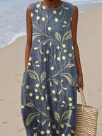 Close-up view of the yellow floral embroidery and relaxed silhouette of the blue sleeveless midi dress.