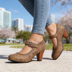 Side view of brown textured Mary Jane heels with brogue perforated trim and buckle strap, worn with cuffed jeans