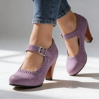 Front-angled view of beige Mary Jane pumps with buckle strap and block heel, paired with rolled denim
