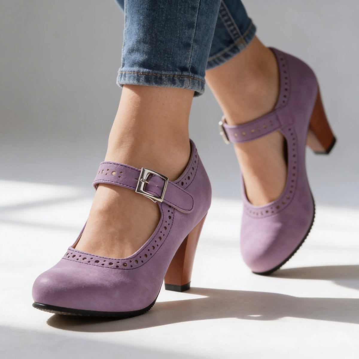 Front-angled view of beige Mary Jane pumps with buckle strap and block heel, paired with rolled denim