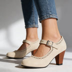 Close-up of black suede Mary Jane pump with perforated detailing and silver buckle on a neutral background