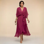 Model wearing a magenta chiffon midi dress with draped V-neckline and flowing handkerchief hem