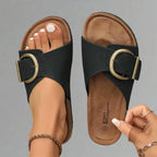 Top-down view of a black pair showing the contoured cork footbed, buckle strap and ridged outsole side by side.