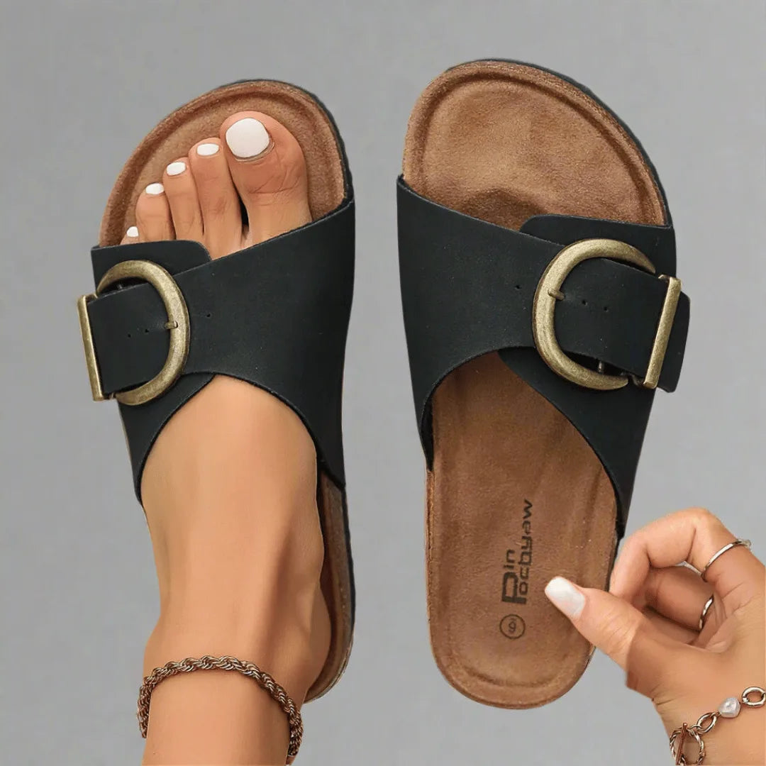 Top-down view of a black pair showing the contoured cork footbed, buckle strap and ridged outsole side by side.