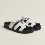 White leather slide sandals featuring the cut-out strap design contrasted against a black sole.