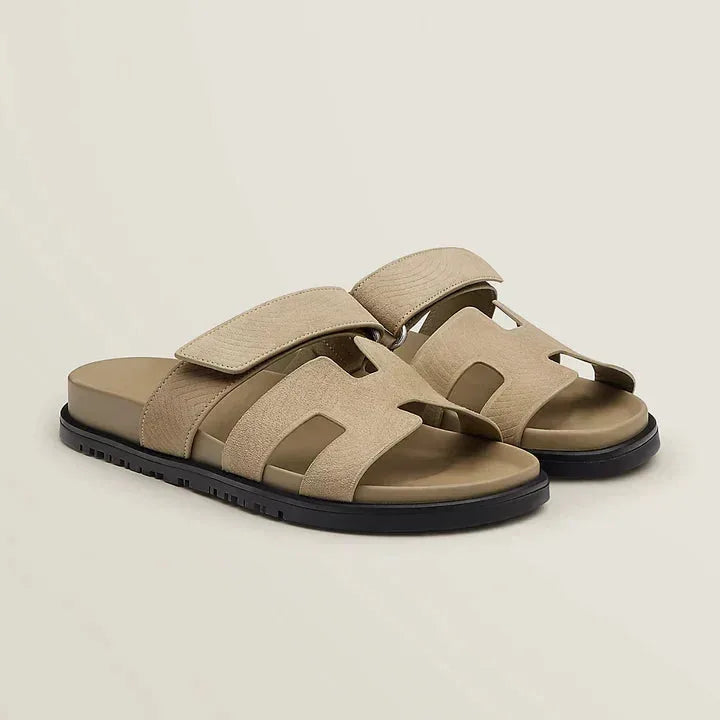 Beige suede-look slide sandals with wide straps and tonal chunky sole, angled front view.