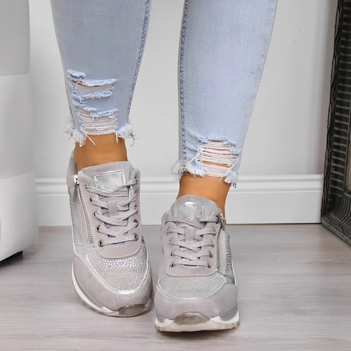 Front-facing view of both grey sneakers showing the laces, zip pulls and sparkly toe caps worn on feet