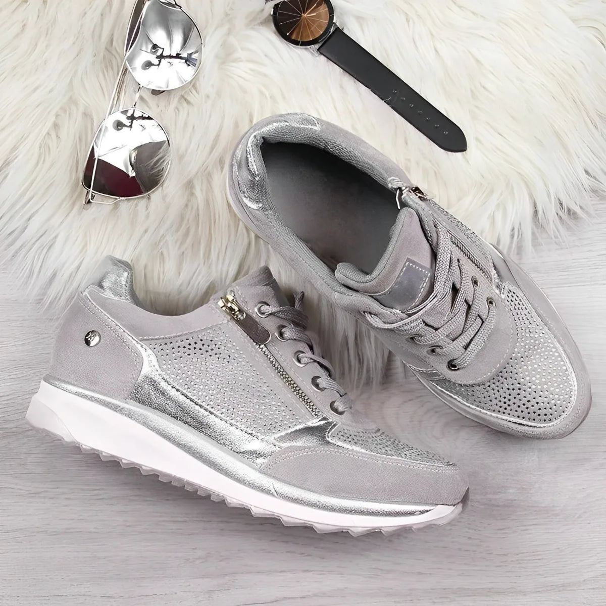 Close-up of beige and champagne metallic sneakers with one shoe held to show the ridged sole