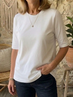 Front view of the white t-shirt showing the relaxed crew neckline and clean hem over dark denim