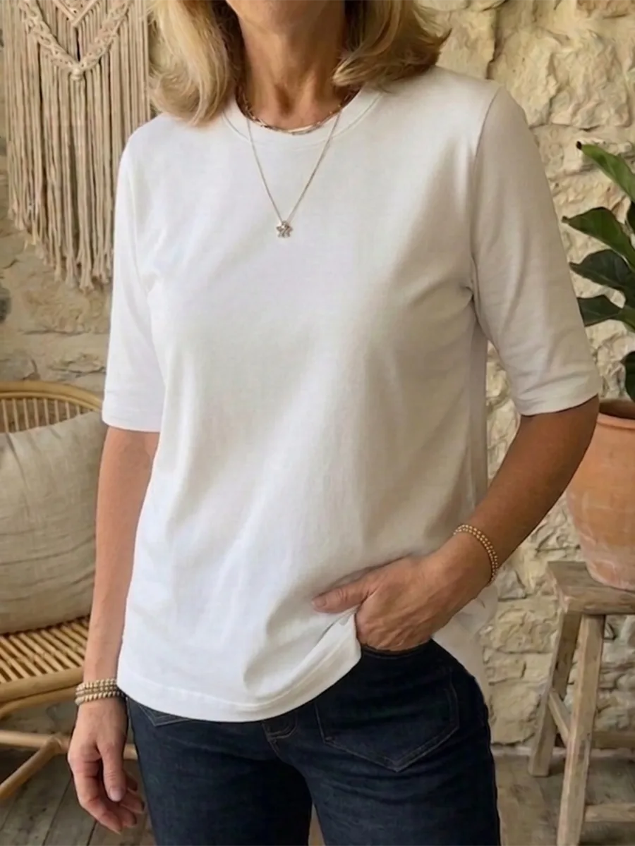 Front view of the white t-shirt showing the relaxed crew neckline and clean hem over dark denim