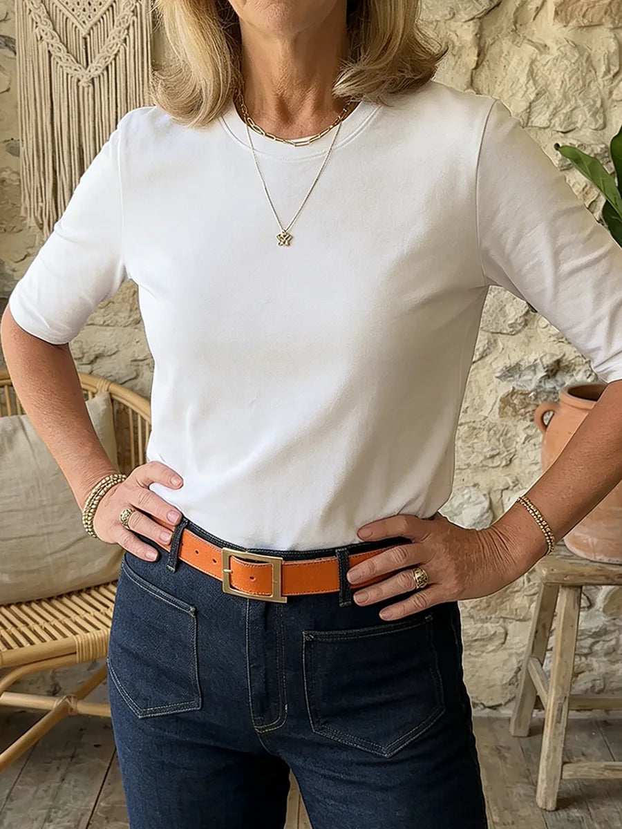 White half-sleeve tee styled with an orange leather belt and gold jewellery, hands resting on hips