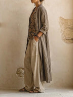 Side profile of the grey linen duster coat worn open over the printed top, showing its flowing floor-length drape