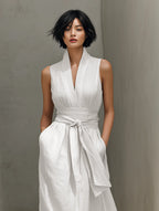 Close-up of the V-neck bodice with shawl collar and belt knotted at the waist of the white linen blend dress