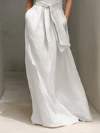 Detail shot of the tied waist belt and flowing A-line skirt panel of the white maxi dress with side pocket