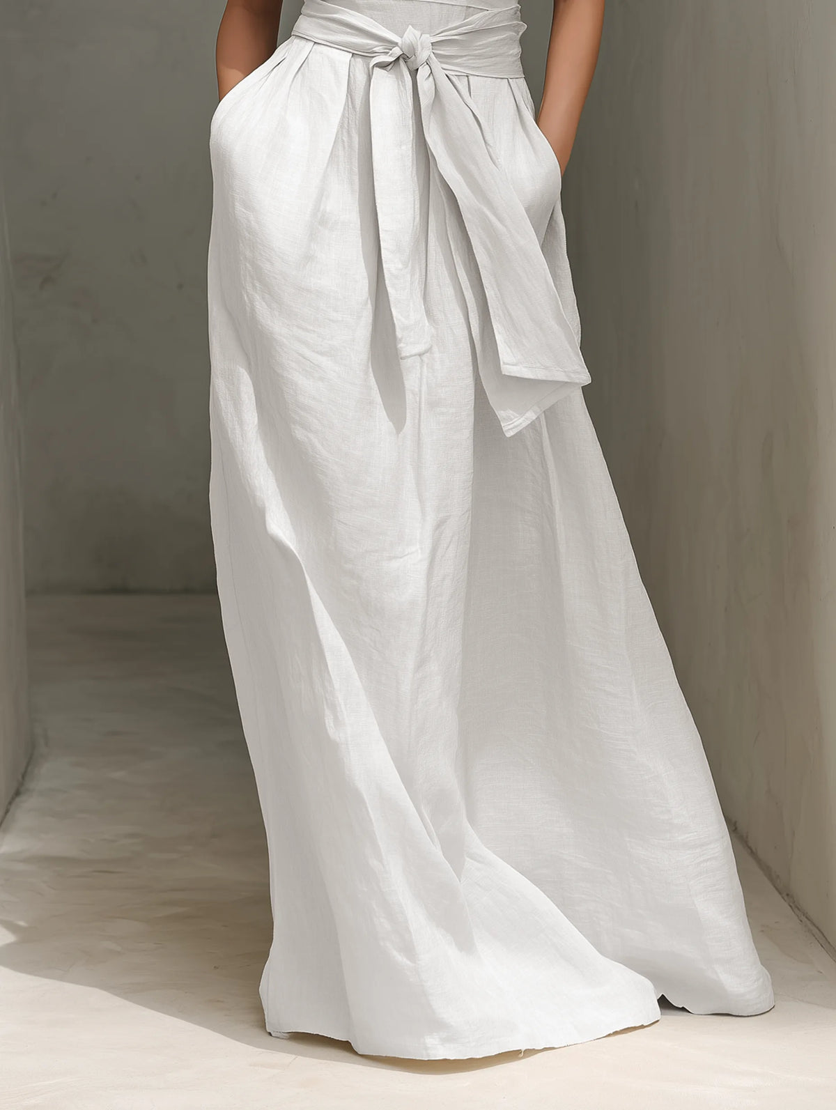 Detail shot of the tied waist belt and flowing A-line skirt panel of the white maxi dress with side pocket