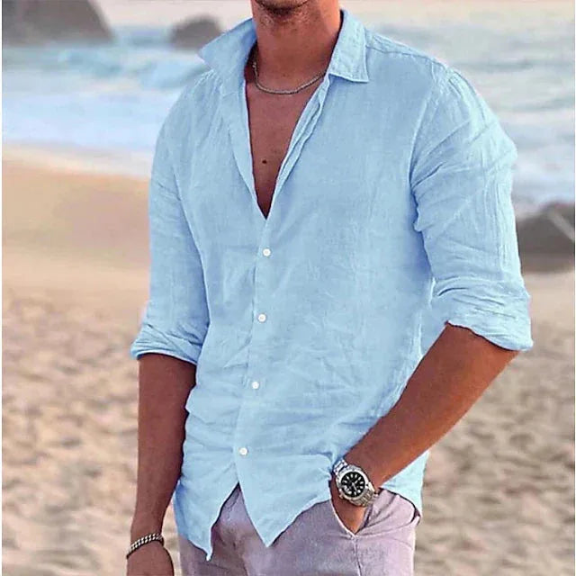 Front view of a light blue linen shirt with button-down collar, worn loosely open on a beach backdrop