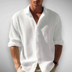 Front view of the shirt in white, buttoned low with sleeves rolled to the forearm