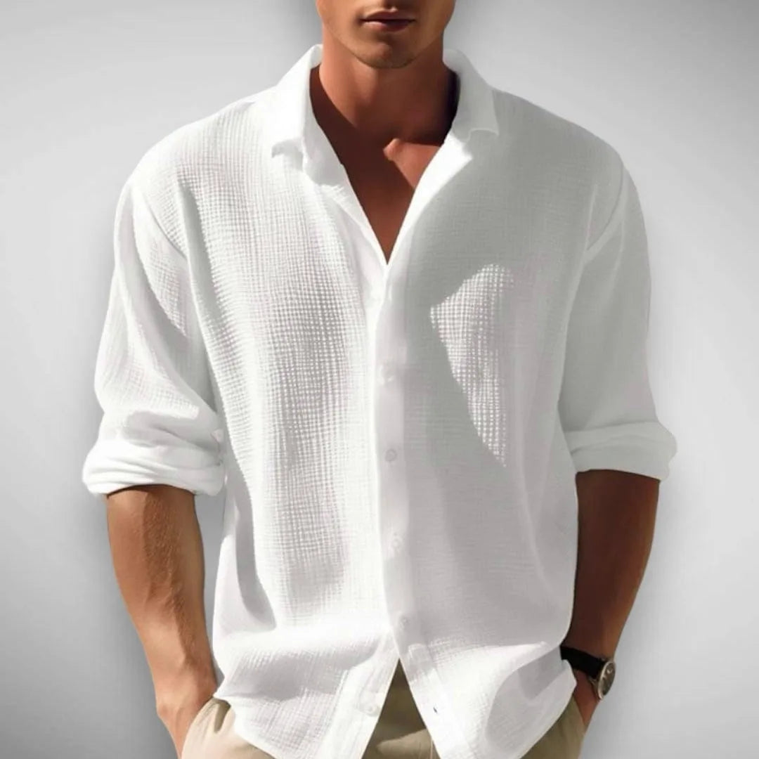 Front view of the shirt in white, buttoned low with sleeves rolled to the forearm