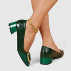 Back view of emerald green croc-embossed block heel pumps with polished patent trim and gold buckle