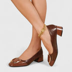 Side profile of brown croc-embossed block heel pumps highlighting the squared toe and gold buckle