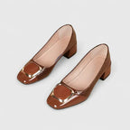 Top-down view of a pair of brown croc-embossed block heel pumps with patent trim and nude lining