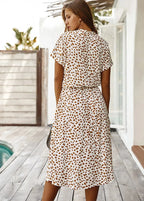Back view of the white midi dress with brown dot print, showing the relaxed fit and tie waist detail