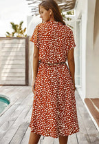 Back view of a rust orange midi dress with a white dot print, showing the drawstring tie waist