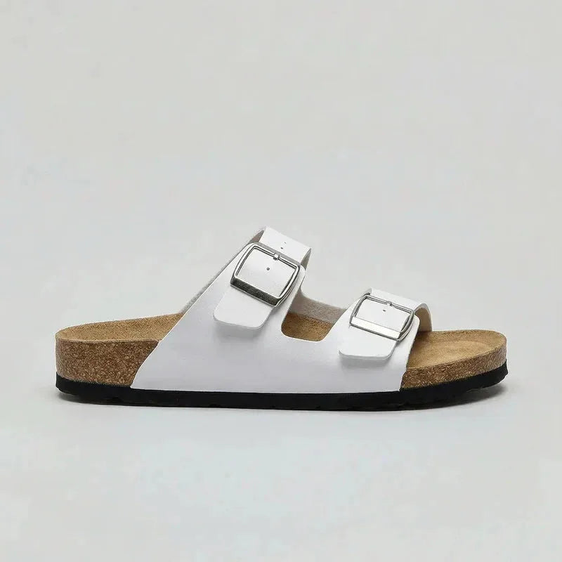 Side view of a white double-strap buckle sandal with silver-tone buckles and natural cork sole