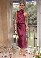 Front view of model in burgundy satin midi dress with draped collar, smiling and holding a bouquet