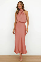 Front view of smiling model in terracotta satin dress showing flowing midi skirt and neutral heels