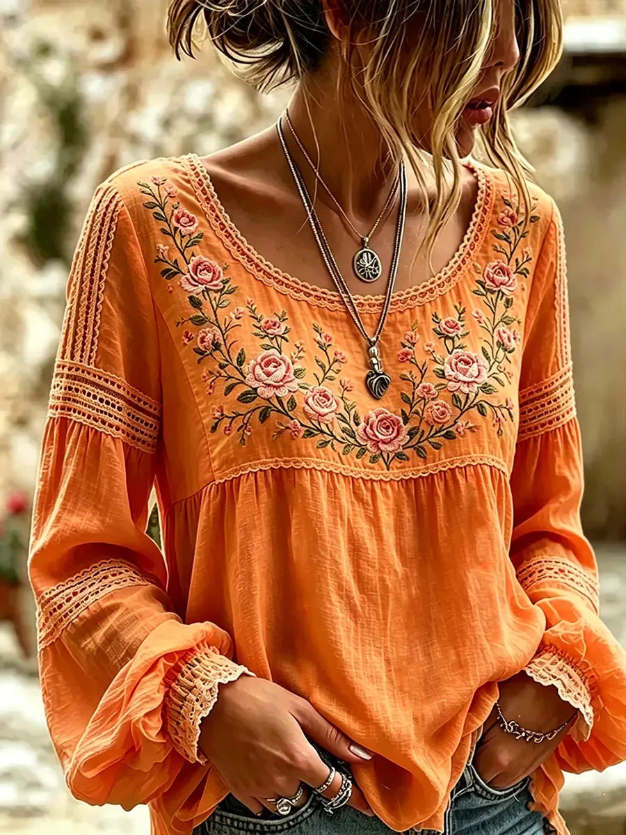 Orange blouse showing the relaxed peasant silhouette with lace cuffs and floral chest embroidery