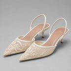 White embroidered mesh slingback heels with pointed toe, floral embroidery and slim kitten heel, side angle view.