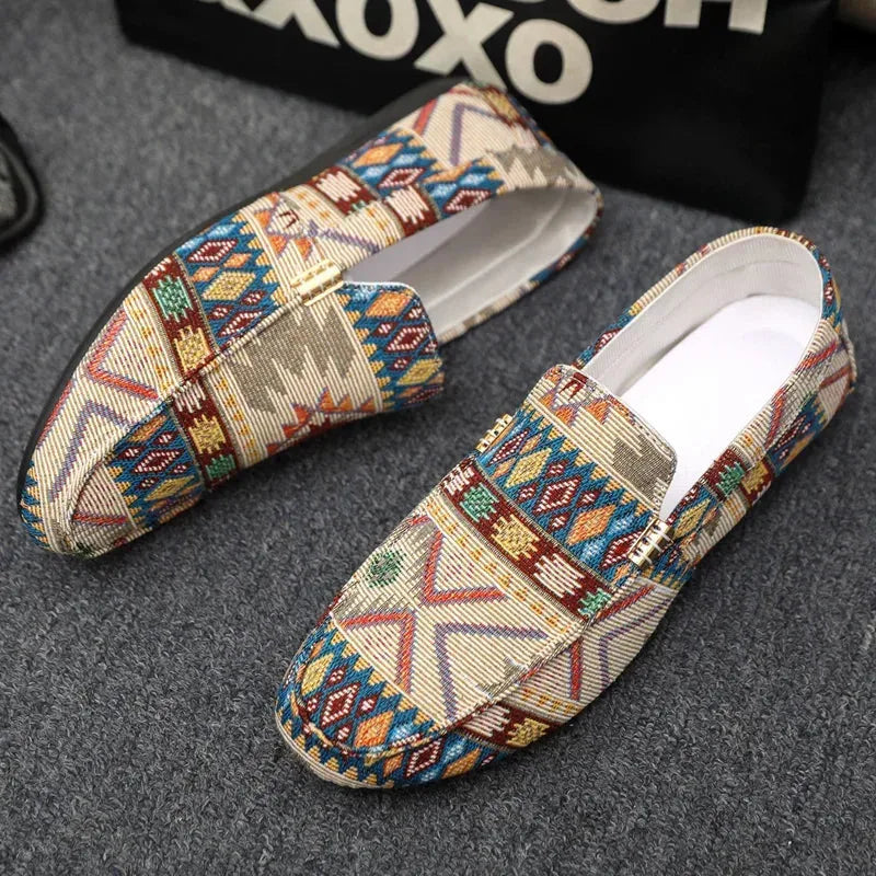 Top-down view of beige patterned loafers with gold buckle detail resting on a grey textured surface
