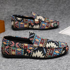 Side profile of two black woven loafers with multicoloured tribal jacquard pattern and flat sole