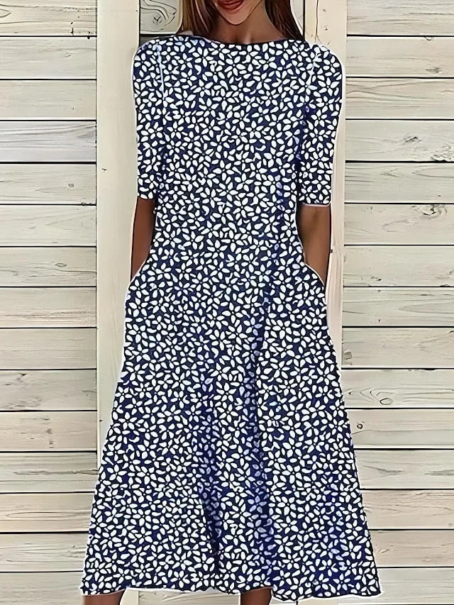 Back view of the navy floral petal print midi dress against a wooden slat background, showing the flowing A-line skirt.
