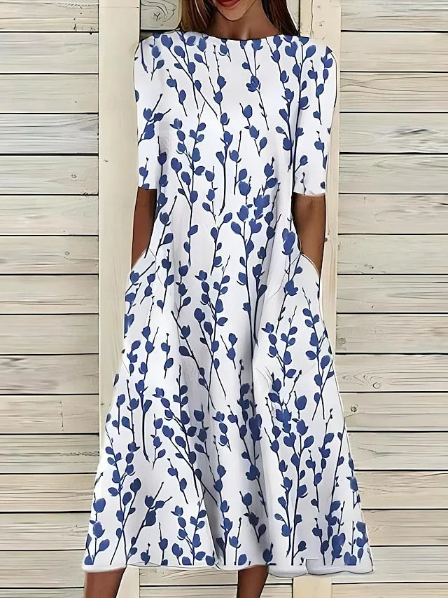 Front view of the white midi dress with navy branch and leaf print, showing the round neckline and side pockets.