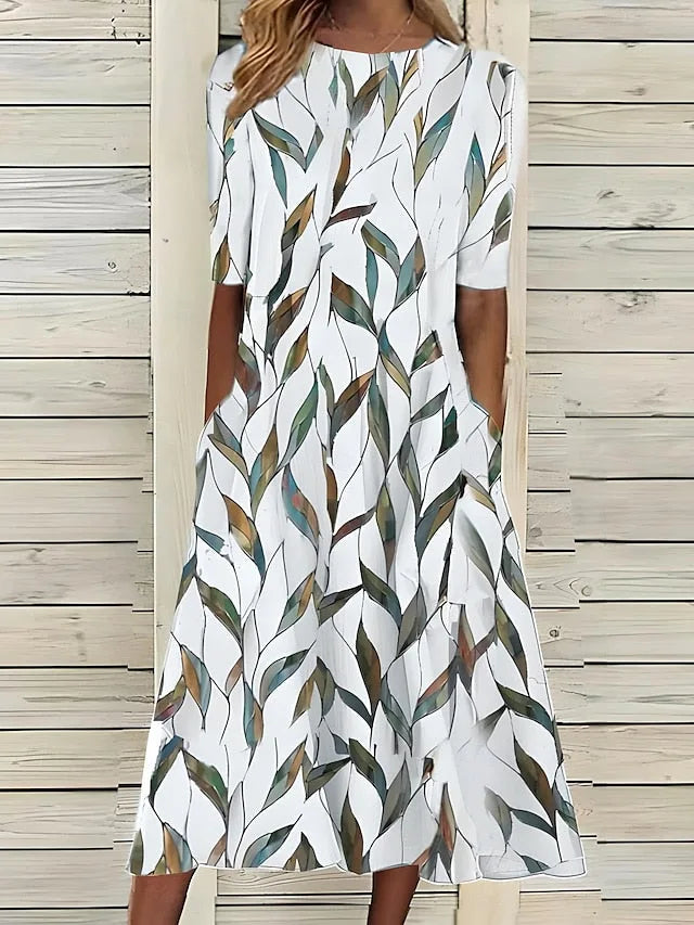 Front view of the white midi dress with green and brown watercolour leaf print, showing the relaxed A-line fit.