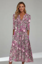 Model wearing the dress in a pink and rose floral print with a layered pendant necklace