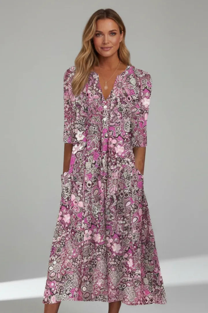 Model wearing the dress in a pink and rose floral print with a layered pendant necklace