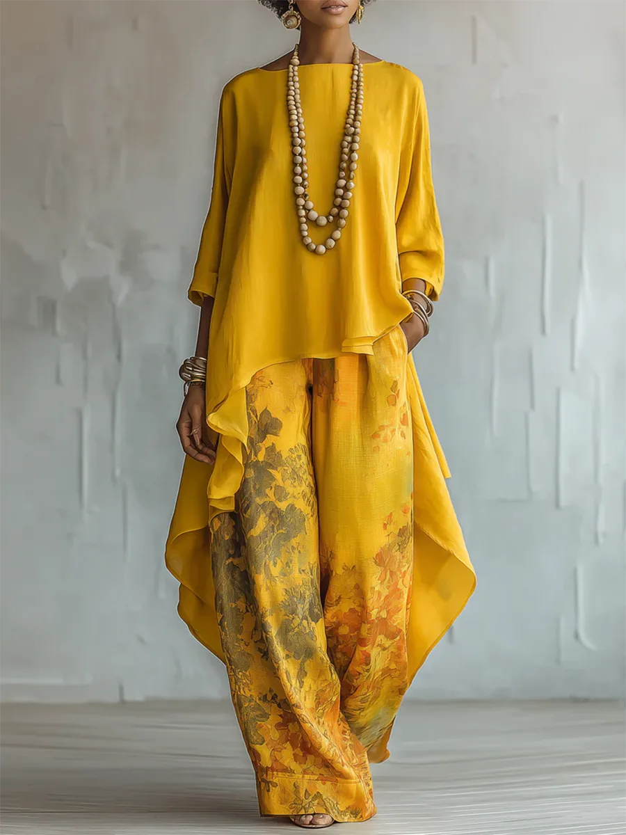Front view of a model in a yellow high-low tunic top with wide-leg floral print pants and a layered wooden bead necklace