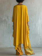 Back view of the yellow tunic showing its flowing high-low hem falling over floral print wide-leg pants