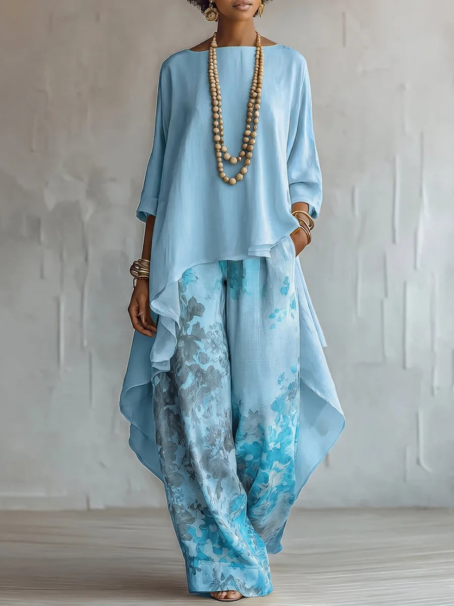 Front view of the pale blue colourway, a relaxed tunic top over floral print wide-leg pants styled with a bead necklace