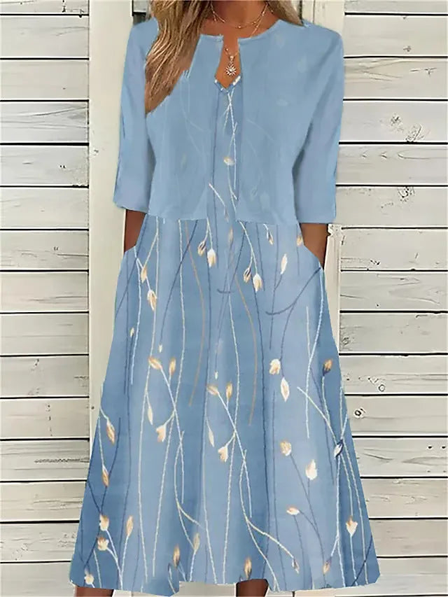 Light blue floral midi dress with matching cropped bolero jacket, worn against a white wooden slat backdrop